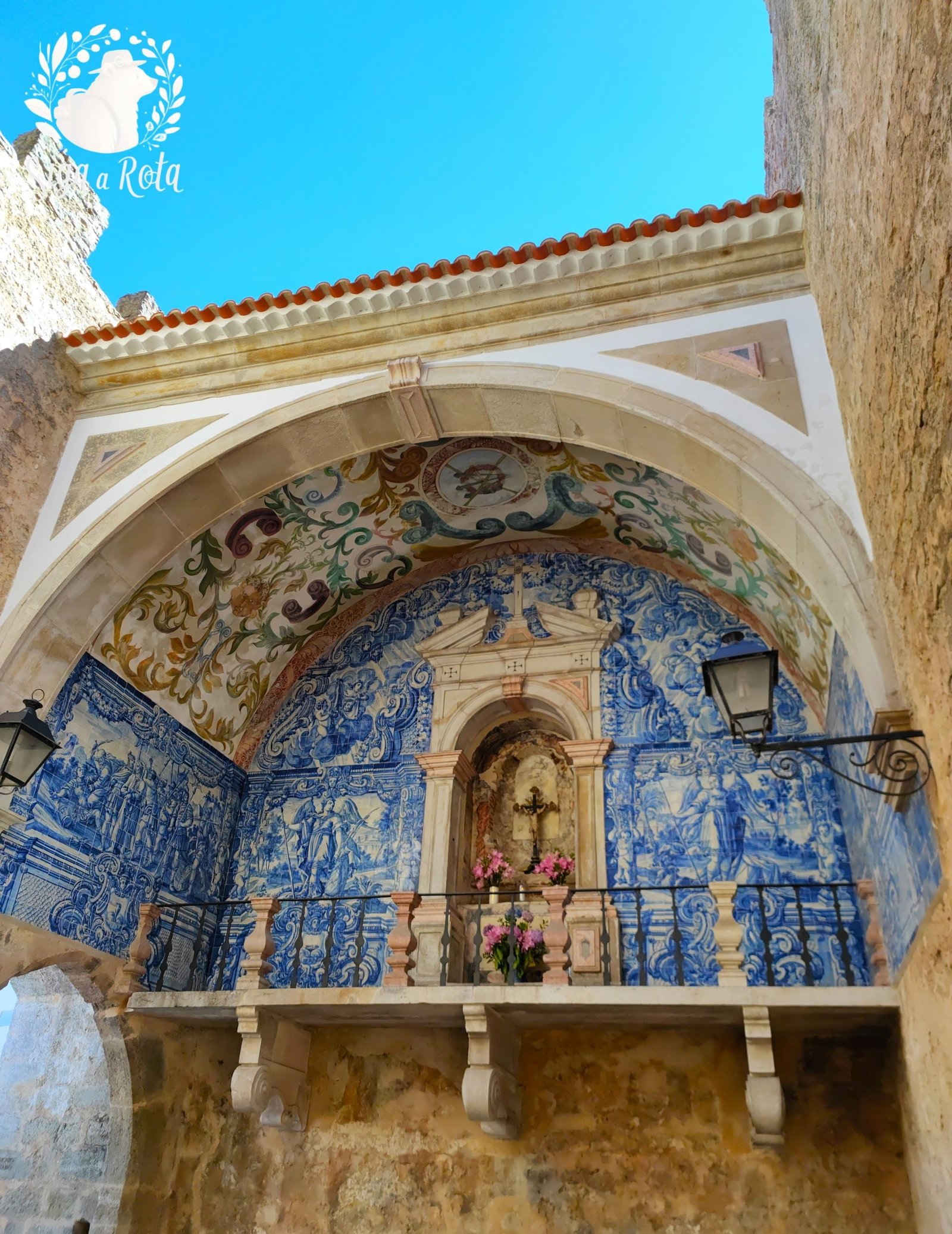Porta da Vila de Óbidos, adornada com azulejos do século XVIII e um oratório dedicado à Nossa Senhora da Piedade, marcando a entrada histórica da vila.