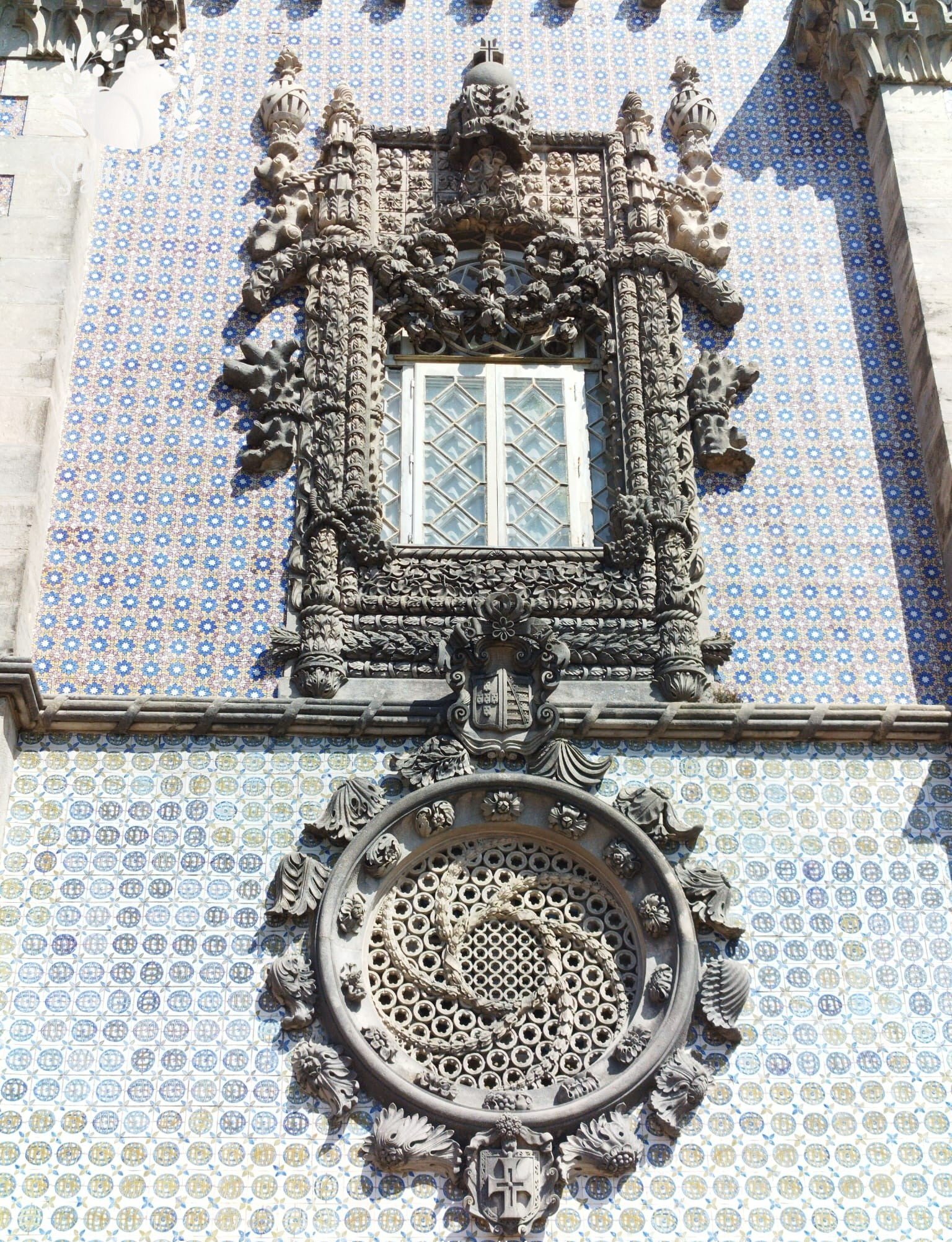 Janelas góticas ornamentadas do Palácio Nacional da Pena, com detalhes arquitetônicos elaborados.