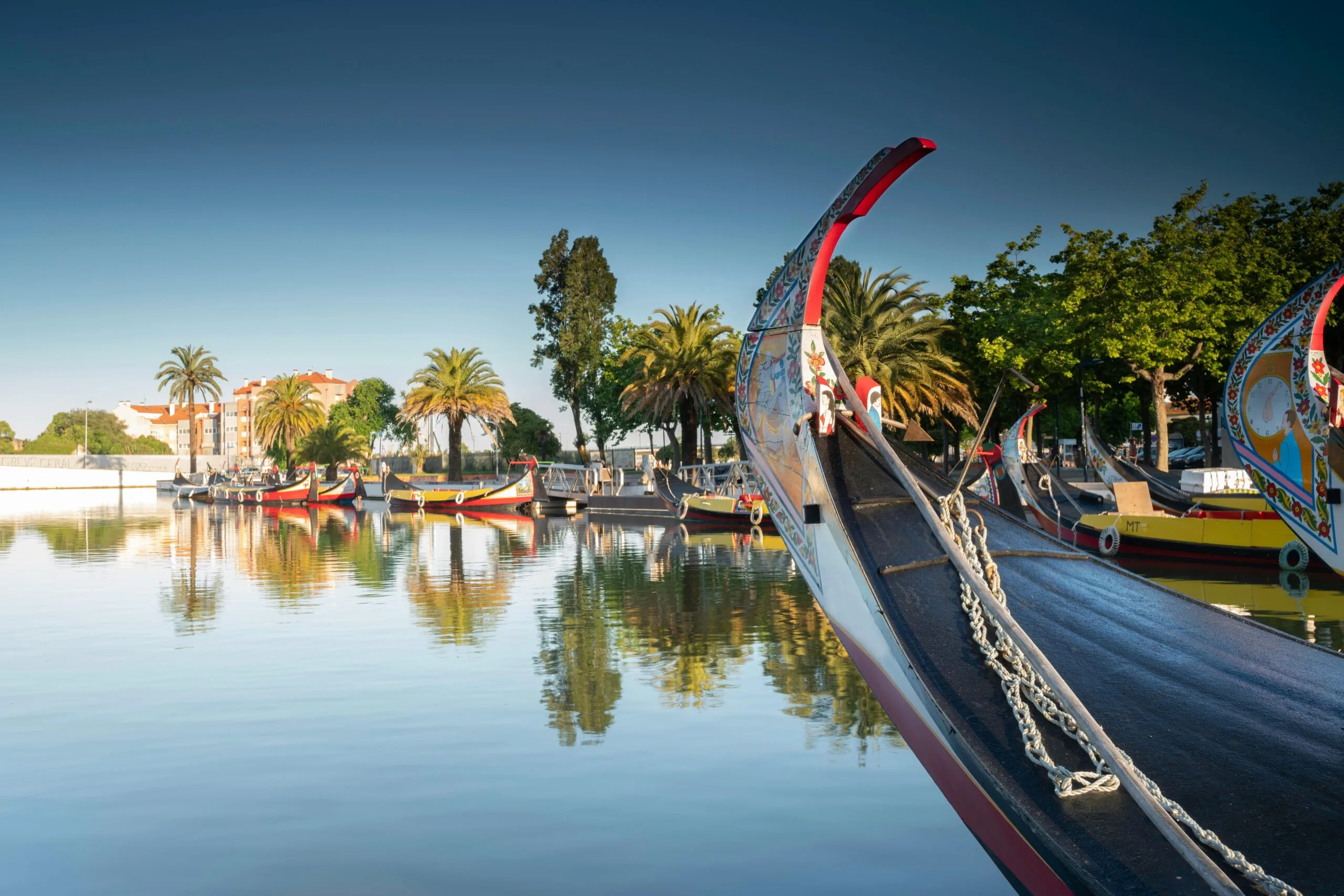Moliceiro tradicional navegando pela Ria de Aveiro, com turistas a bordo apreciando a paisagem.