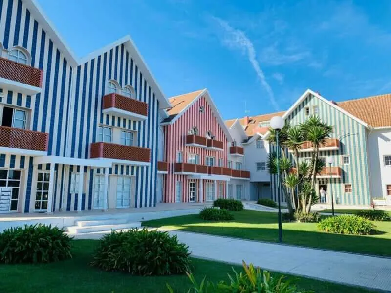 Visitantes relaxando na Praia da Costa Nova, com suas casas coloridas ao fundo.