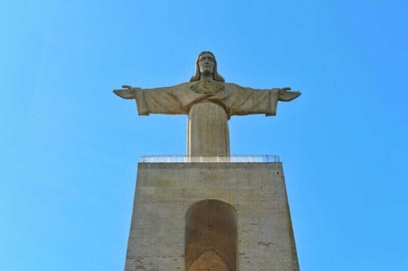 Monumento do Cristo Rei em Almada, com sua estátua de 28 metros sobre um pedestal imponente, oferecendo vistas panorâmicas de Lisboa e do Rio Tejo.