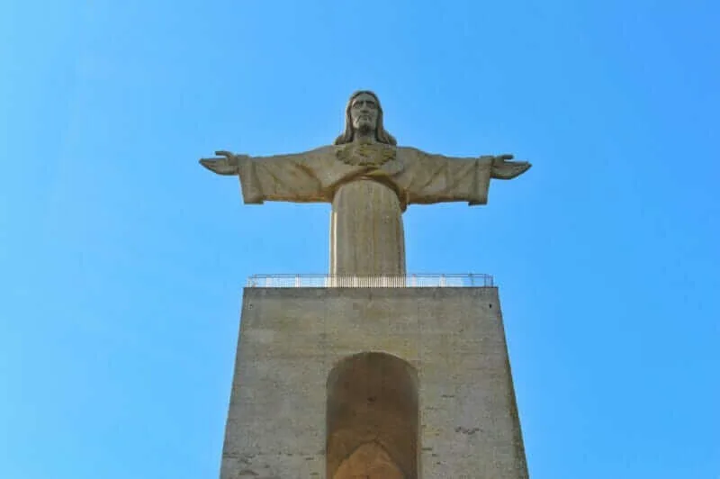 Monumento do Cristo Rei em Almada, com sua estátua de 28 metros sobre um pedestal imponente, oferecendo vistas panorâmicas de Lisboa e do Rio Tejo.