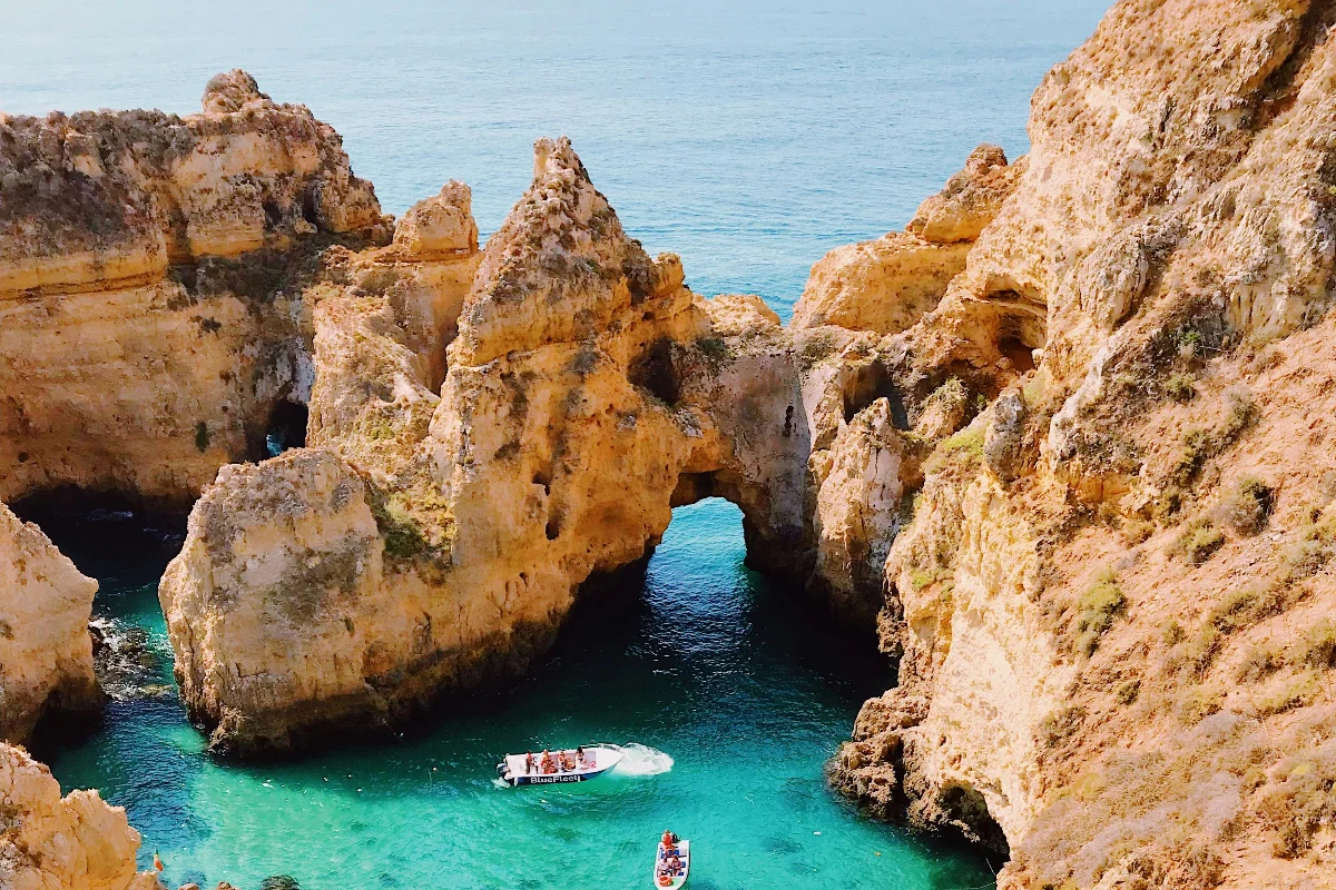 Barco navegando pelas grutas do Algarve, com águas cristalinas e formações rochosas