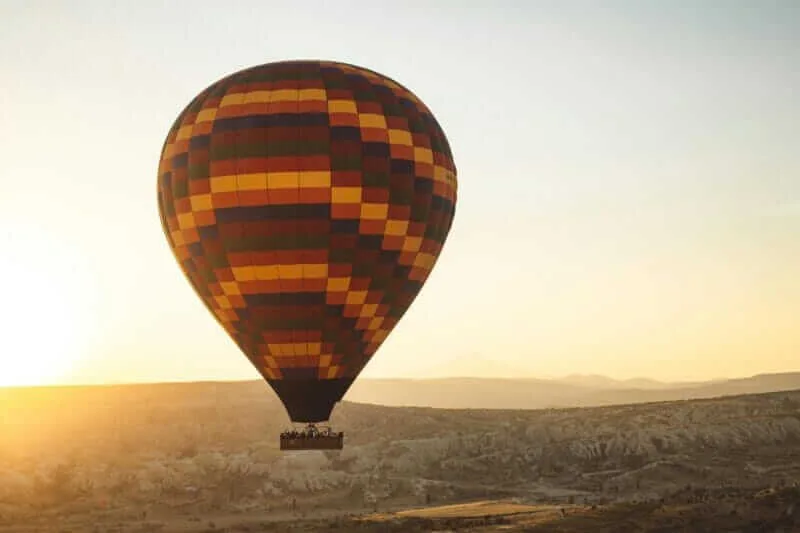 Balão sobrevoando a planície do Alentejo ao amanhecer, oferecendo vistas panorâmicas da paisagem rural de Portugal