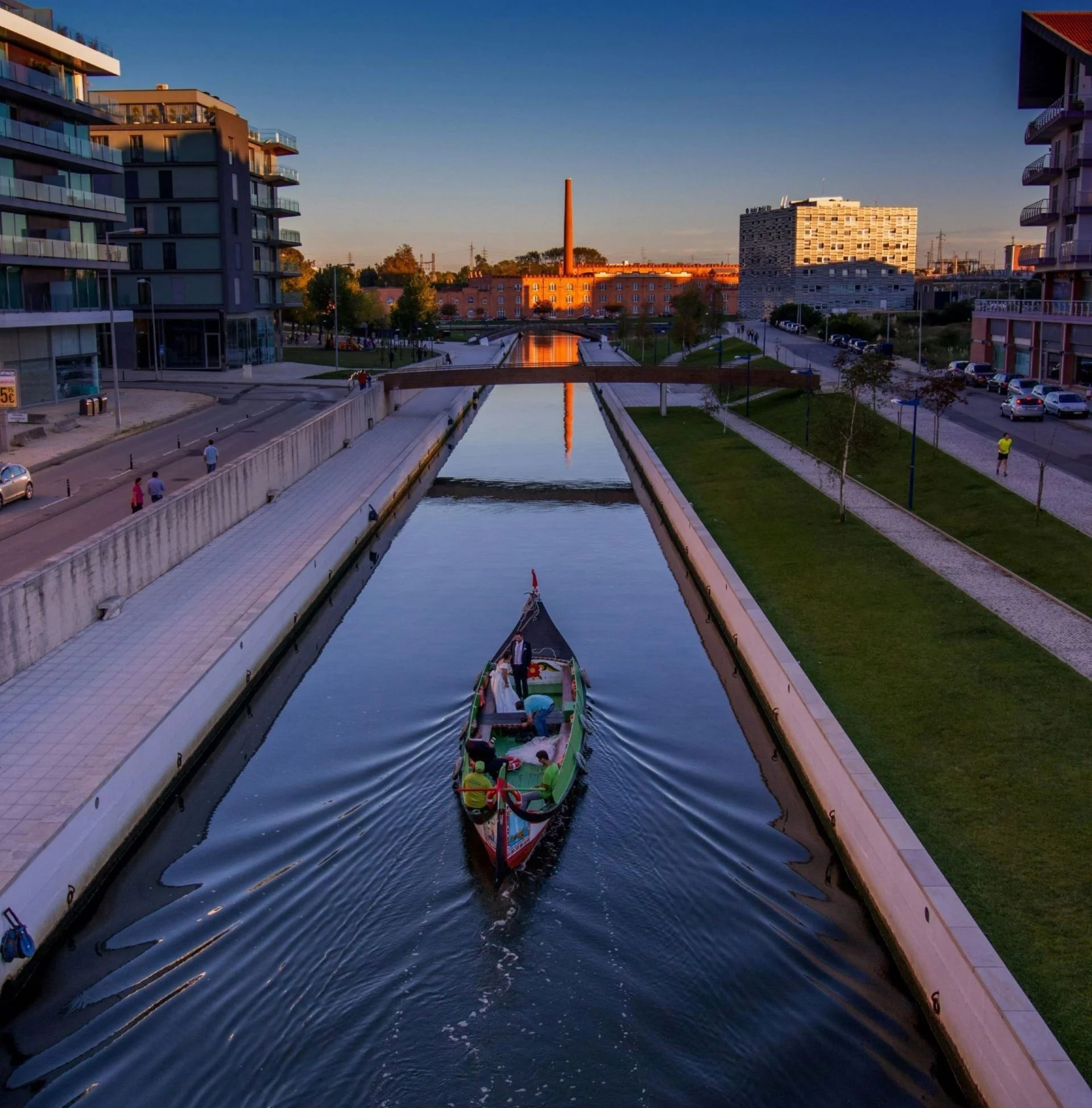 Moliceiro tradicional navegando pela Ria de Aveiro, com turistas a bordo apreciando a paisagem.