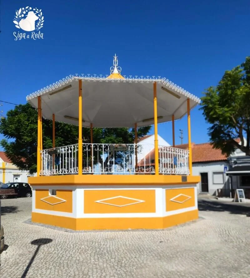 Coreto tradicional no Largo do Rosário, cercado por vegetação e casas históricas.
