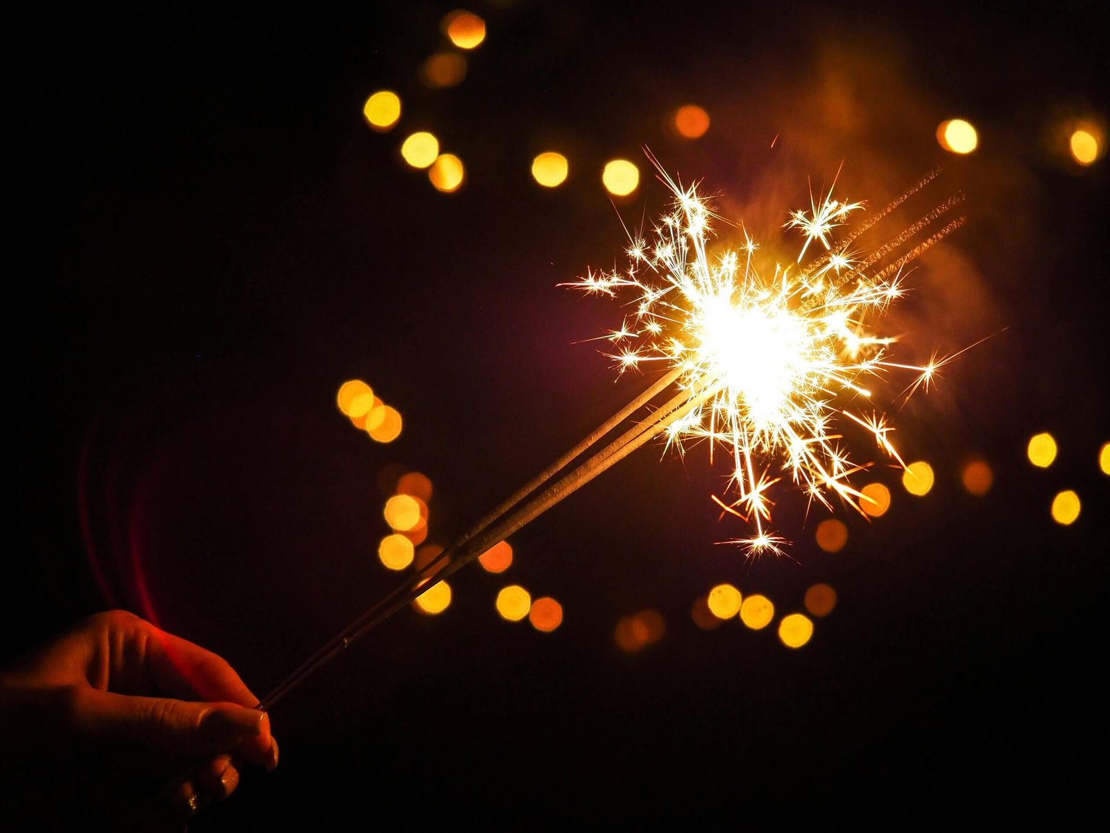 Comemoração de Ano Novo em Portugal com fogos de artifício iluminando o céu e pessoas celebrando ao ar livre.