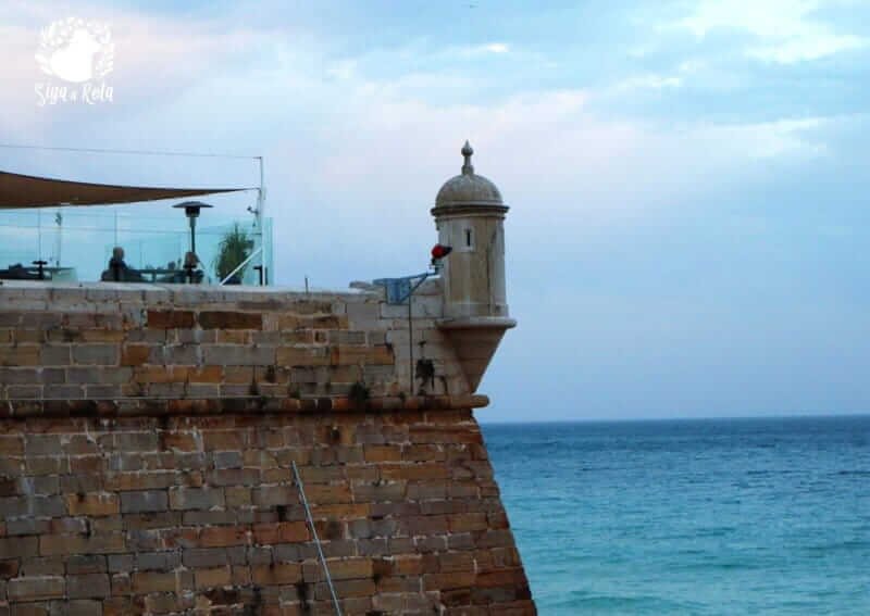 Turistas caminhando pelas muralhas e apreciando as exposições dentro da Fortaleza de Santiago, em Sesimbra.