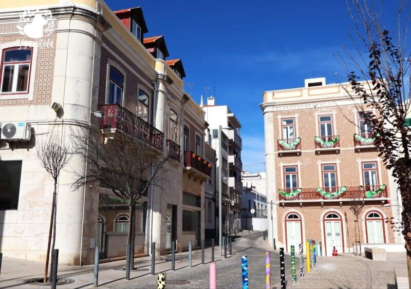 Ruas estreitas e coloridas de Sesimbra com casas tradicionais e detalhes arquitetônicos.