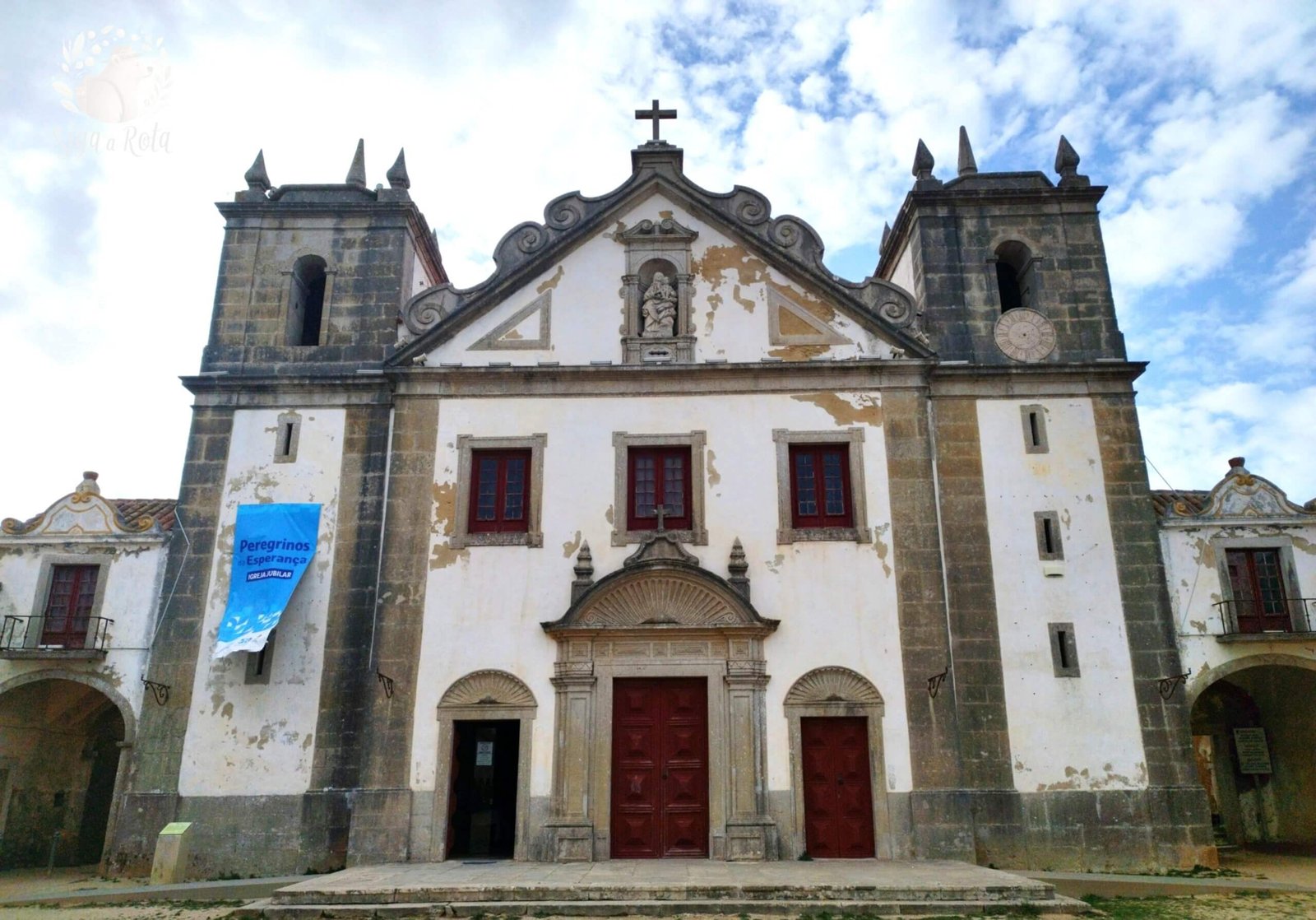 : Vista frontal do Santuário de Nossa Senhora do Cabo Espichel, com sua arquitetura histórica em destaque.