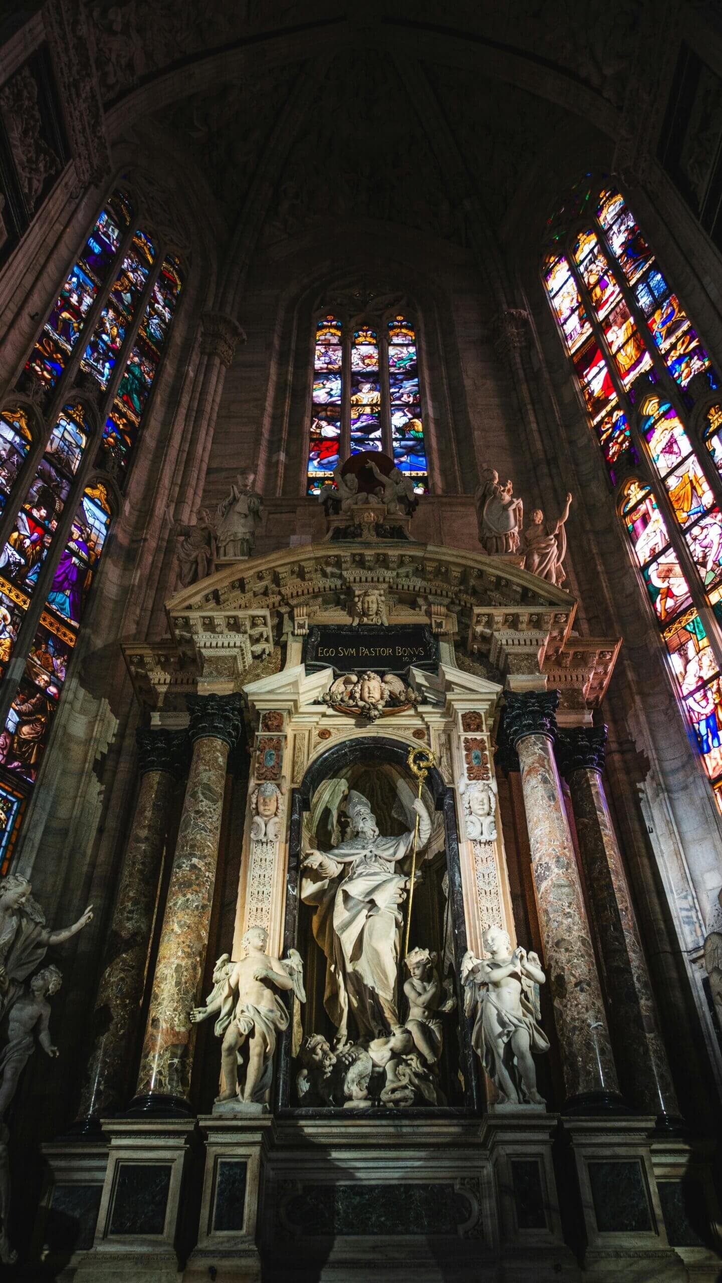 Interior do Duomo de Milão com seus vitrais coloridos e colunas imponentes.