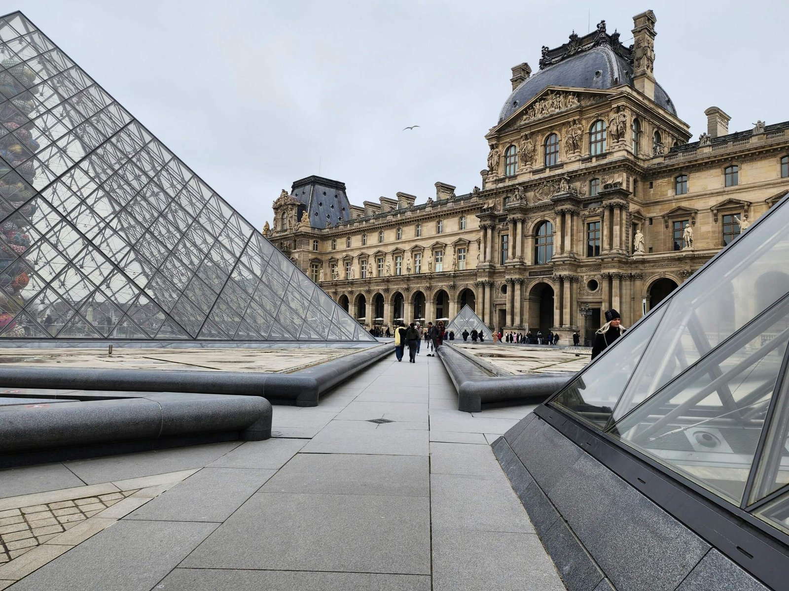 Galerias do Museu do Louvre com visitantes admirando obras icônicas.